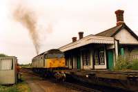 A 47 passes through the well preserved Felixstowe Beach station in 1990 with a container train. The unpreposessing cabin on the left was the signalbox.<br><br>[Ewan Crawford //1990]
