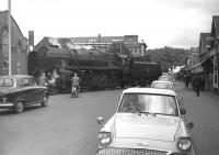 BR Standard class 9F 2-10-0 no 92239 crosses the road on its way out of Southampton Docks in 1963, just as a boy-racer of the day revs his Ford Anglia for the off.... (after donning his <I>shades</I>).<br><br>[Robin Barbour Collection (Courtesy Bruce McCartney) 17/07/1963]