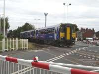 Northern Rail's 15.07 service to Wakefield Kirkgate comprising single unit 153301 leading a Class 150/2 DMU departs Streethouse Station over Whinney Lane level crossing   <br><br>[David Pesterfield 14/08/2009]