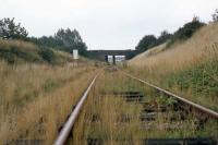 Further to Ken Strachan's picture of the Witham-Maldon line trackbed today [see image 26138], here is the corresponding scene from approximately the same spot on 28th August 1977. The road bridge is the point of comparison. The sign on the left warns industrial rail traffic from the Rom River factory beyond the bridge that it must not pass through the gates (behind the photographer) that mark the beginning of British Rail jurisdiction.<br><br>[Mark Dufton 28/08/1977]