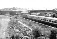 A Glasgow - Leeds train shortly after restarting from Dumfries in 1982, passing the site of Dumfries shed, with the buildings now demolished. This view from St Mary's Street bridge had not been possible prior to demolition of the old shed.<br><br>[John Furnevel 18/06/1982]