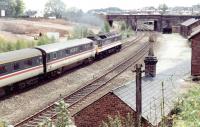 A dead electric train is dragged south through Dumfries by a class 47 on a Sunday morning in June 1991, with locomotive and stock in immaculate BR InterCity livery. The train is passing preparatory works for the new Dumfries & Galloway police HQ on the site once occupied by Dumfries shed.<br><br>[John Furnevel 23/06/1991]