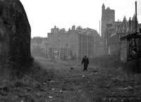 One man and his dog approaching along the Caledonian trackbed from the direction of Merchiston station in 1972. View is south west, with Dundee Street footbridge [see image 29621] a short distance behind the camera. On the right is Angle Park Terrace with the tower of St Michael's Church, standing in the background at no 1 Slateford Road. [Editor's note: A definite 'Kitchen Sink' feel about this one - listen for the church bells tolling, a Salvation Army band playing and the sounds of a Mr Burton murdering his trumpet in one of the top floor tenement flats in the background. Only problem is it's not raining....]<br><br>[Bill Jamieson //1972]