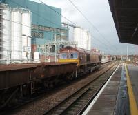 With the giant Unilever works complex forming a backdrop, 66207 gets a load of open wagons and container flats on the move through Bank Quay station. The train has just left Arpley Yard at the south end of the station and is heading north towards Winwick Junction. <br><br>[Mark Bartlett 04/11/2010]