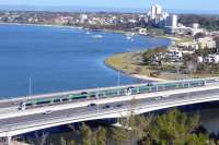 View from King's Park over South Perth with a Transperth emu bound for Mandurah in September 2010. These trains do not serve Perth Central, instead burrowing down a new line via Perth Underground and Esplanade stations. This line is of recent construction and uses the median of the freeway at this point.<br>
<br><br>[Colin Miller 26/09/2010]