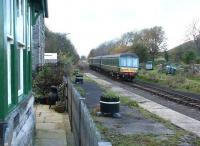 A Redmire - Leeming DMU passing the former Wensley station on 3 November 2004. The old station has been converted to a holiday cottage, but with the original railway theme retained. To the left beyond the bay window, now the master bedroom, was the private waiting room once used by  local landowner Lord Bolton. The Wensleydale Railway continues to work on restoration of the full 22 mile route from the ECML at Northallerton to the S&C at Garsdale.<br><br>[John Furnevel 03/11/2004]