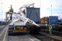 A lorry-mounted crane transfers containerised timber from road to rail at Coatbridge Freightliner terminal, as part of a 2001 demonstrator project managed by the photographer for Scottish Enterprise.<br>
<br><br>[David Spaven //2001]