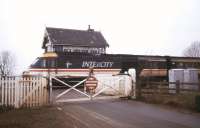 An InterCity 125 speeds over the level crossing at St James Deeping, located on the former GN route between Peterborough and Spalding. The line was in use as a diversionary route in January 1991 during engineering work on the ECML. The instruction on the gate makes an interesting alternative to <I>Pull</I>. [Note: Despite serving the village of Deeping St James, Lincolnshire, the station (closed to passengers in 1961) and signal box both carried the name St James Deeping.] <br><br>[Ian Dinmore 27/01/1991]