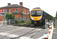 Shortly after leaving Northallerton station on 9 July, the 11.35 Manchester Airport - Middlesbrough has turned north east onto the former Leeds Northern route heading for Teesside. The train is about to run over Low Gates level crossing on the busy A167, with the town's High Street off to the left. The kitchen showroom on the up side was once Northallerton Town station, opened by the Leeds Northern Railway in June 1852 and closed less than 4 years later on 1 January 1856.   <br><br>[John Furnevel 09/07/2012]