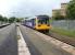 A Northern Class 142 arrives at Wigan Wallgate with a service to Manchester Victoria on 16 June 2012. The view is west and the embankment and overbridge carrying the WCML can be seen in the left background.<br><br>[John McIntyre 16/06/2012]