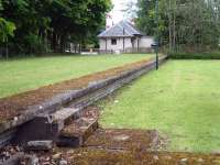 Looking from track level along the platform to the well maintained and occupied station building at the former Dornoch Station, showing both structures still intact 53 years after closure. <br><br>[David Pesterfield 23/06/2013]