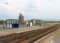 Three items of interest in this view of Seascale's southbound platform. The old Furness Railway water tower is a prominent local landmark. To its right is the old goods shed, which is now the town's Sports Centre. On the platform itself is a <I>Harrington Hump</I> which provides level access to trains. These were pioneered at the station of the same name, just north of Whitehaven, and provide a cost effective alternative to raising low platforms along their full length. They are appearing at various Cumbrian Coast stations and elsewhere in the UK. <br><br>[Mark Bartlett 27/07/2013]