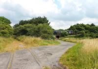 Looking north east along the trackbed of the Eskmeals gun range branch towards the junction with the Cumbrian Coast line as a Carlisle to Barrow service passes on 27 July 2013. The Vickers Gun Range Sidings box that controlled the branch access closed in 1983. It had an unusual Ransomes and Rapier <I>horse rake</I> 11-lever frame that is now preserved at the NRM York. [See image 44051] for a view in the opposite direction. Level crossings map reference SD088925<br><br>[Mark Bartlett 27/07/2013]