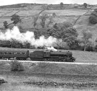 Just over two years after its acquisition by the Keighley and Worth Valley Railway, ex Swedish State Railways WD 2-8-0 No. 1931 heads an afternoon train up the valley between Haworth and Oxenhope, thought to be on a Sunday in July 1975. Since then the loco has acquired a four axle tender and now runs with the fictitious identity of BR No. 90733. <br><br>[Bill Jamieson /07/1975]