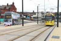 A 4-car Metrolink tram leaves the old railway formation at Oldham Mumps and climbs to the interchange stop, one of four new Metrolink boarding points through the town centre.  A large railway bridge once dominated the background here and the location, including the surviving building on the left, featured in a Railscot mystery image which ran in March 2012 [see image 37965]<br><br>[Mark Bartlett 13/02/2014]