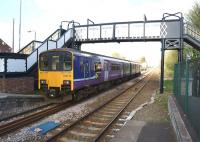 A view east from the platform at Rainhill on 19 April 2014 with a Manchester bound service passing under the footbridge. Rainhill signal box can be seen beyond the train.<br><br>[John McIntyre 19/04/2014]