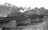 Scene at Ribton Bridge on the River Derwent, east of Camerton on the Workington - Penrith line in the 1950s. Ivatt 2MT 46489 has recently arrived with coal empties, which it is pushing back towards the sidings for Ribton Hall Colliery. The locomotive was based at Workington between 1954 and 1959 before moving to Upperby, from where it was withdrawn in November 1963. The line between Workington and Keswick closed in 1966. [Ref query 7169]<br><br>[Bruce McCartney Collection //]