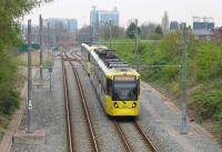 <I>Over the top!</I> Two 3000 series trams heading for East Didsbury drop down the steep slope alongside Old Trafford Metrolink Depot to regain the original Midland Railway formation. Behind them is a depot access point and beyond that the Trafford Bar junction with the Altrincham line and the <I>diveunder</I> for Manchester bound trams. [See image 51062]<br><br>[Mark Bartlett 24/04/2015]