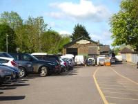 Looking west along the car park at Sherborne Station on 12 May, with the former goods shed at the far end. A large replica totem shows it is now called <I>The Railway Shed</I> and being used by a fibreglass fabricator. <br><br>[David Pesterfield 12/05/2015]