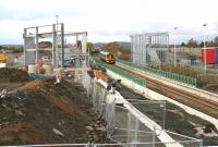 View over part of the construction site which will become the new Edinburgh Gateway interchange on 11 November 2015, seen from the down side of the line. The 0941 Inverness - Edinburgh is about to run south through the platforms while in the background the 1300 Edinburgh - Dundee is heading for the Forth Bridge.<br><br>[John Furnevel 11/11/2015]