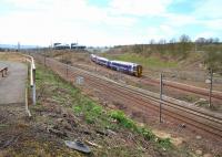 Looking south towards Millerhill Yard on 17 April 2016, showing the considerable clearance of vegetation that has recently been carried out along the embankment. The entrance to the depot from Whitehill Road is on the left. In the background a Waverley bound train is approaching from the Shawfair direction.<br><br>[John Furnevel 17/04/2016]