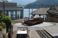 The compact arrangements at Vitznau, on the shore of Lake Lucerne. The depot is accessed by the turntable, which has a straight and curved line and is kept busy throughout the day. Here a vintage carriage that has just returned from a charter trip to Rigi summit is returned to its depot road by the resident shunter. The rail platforms are in the foreground with the ornate lake steamer station behind.<br><br>[Mark Bartlett 27/06/2016]
