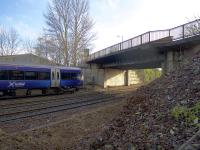 An Alloa - Glasgow Queen Street service about to pass under the A905 Kerse Road overbridge. Plans have been submitted for its replacement as part of the preparation for electrification. The current bridge could accommodate 4 tracks but its replacement will span only the existing 3 tracks.<br><br>[Colin McDonald 30/01/2017]