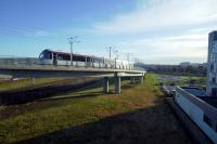 An airport - bound tram climbs from Edinburgh Park in the strong early morning sun on 27-2-17.<br><br>[Colin Miller 27/02/2017]