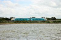 An Arriva Class 175 nears Rhyl station running along the embankment to the west of the station on 27th July 2017. The train is passing the Marine Lake and the Rhyl Miniature Railway runs between the lake and the embankment wall. [See image 60271]<br><br>[Mark Bartlett 27/07/2017]