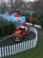 A steam-outline locomotive draws its train round the narrow gauge circuit of the Christmas Fair in Princes Street Gardens East on 28th November 2017.  Waverley Station is beyond the bushes in the distance.<br>
<br>
<br><br>[Bill Roberton 28/11/2017]