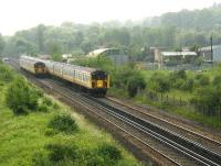 An approaching 12-car Brighton – London Bridge service passes a Horsham train on the Quarry Line just south of Stoats Nest Junction  in the Summer of 2002. The area on the right, consisting of wasteland and a scrapyard, had been occupied by Coulsdon North station and carriage sidings until closure in 1983 [see image 43249]. (Rail travellers continued to be well served by other nearby stations including Coulsdon Town and Coulsdon South). The location has since been redeveloped and the A23 Coulsdon relief road now runs through the site.<br><br>[Ian Dinmore 18/06/2002]